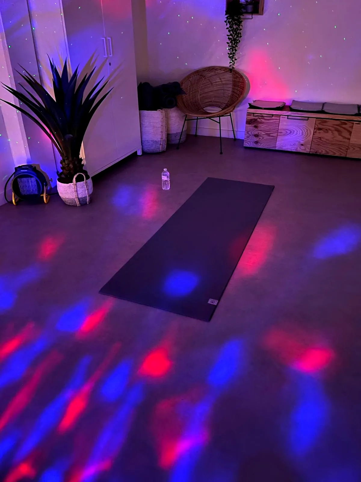 A mat in a dark studio with coloured lights moving across the floor