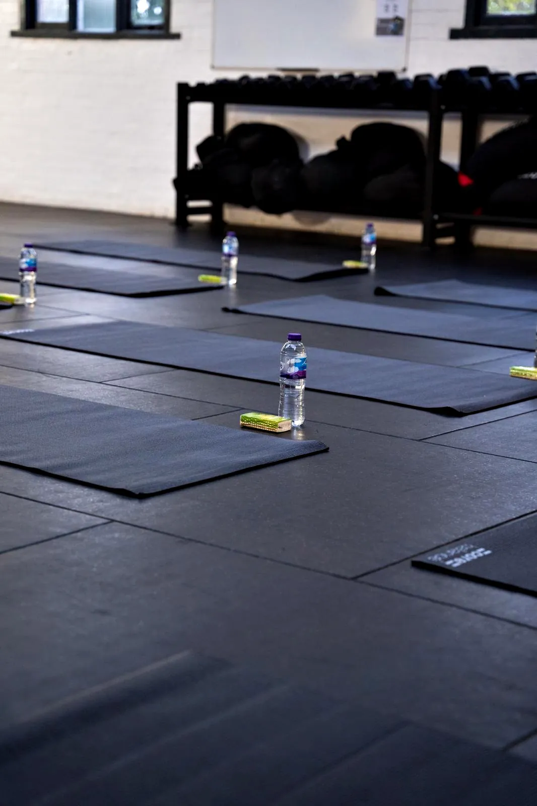Mats and water bottles laid out in a gym before a session