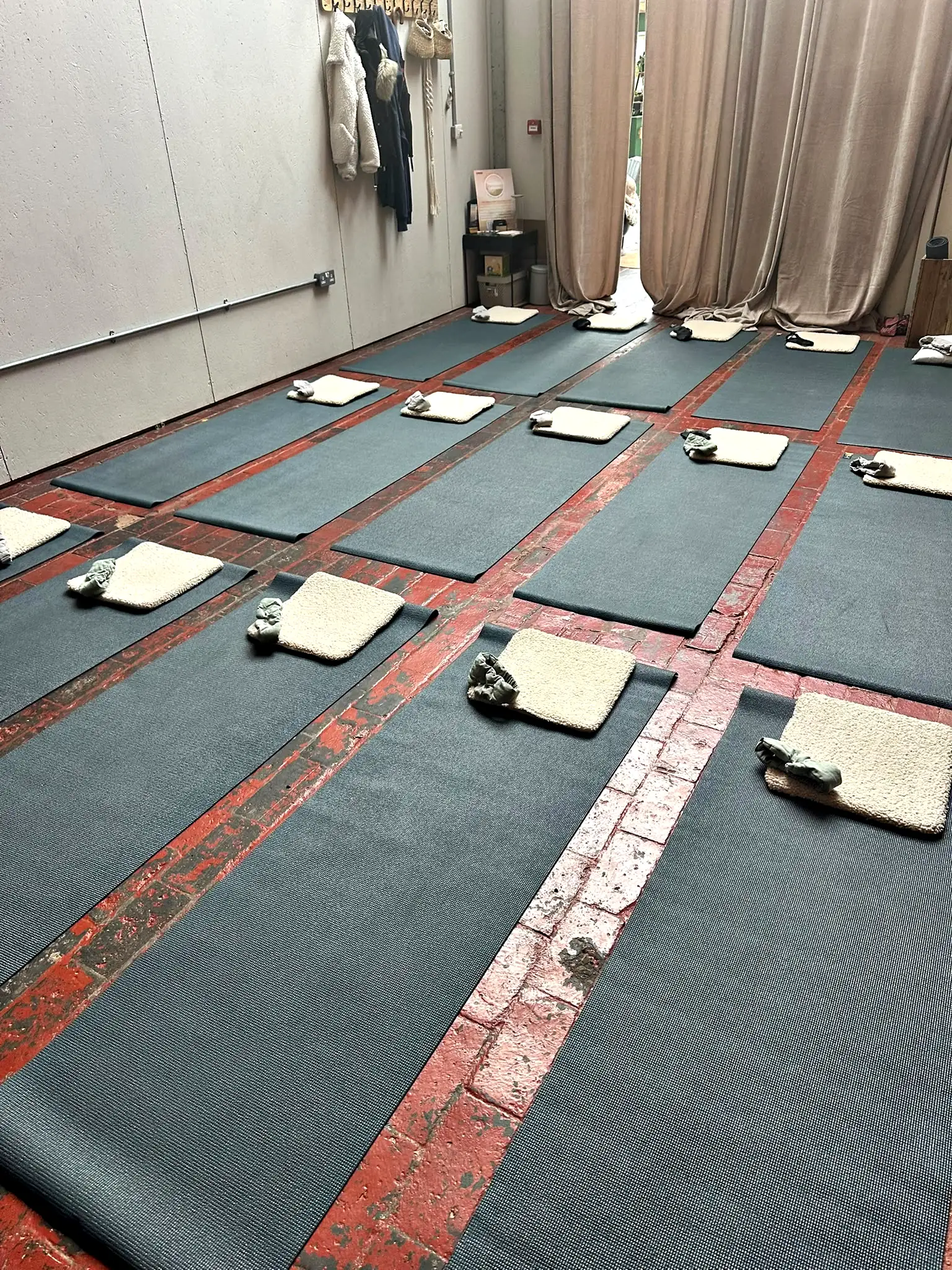 A long studio with a red striped floor, mats and cushions laid out ready